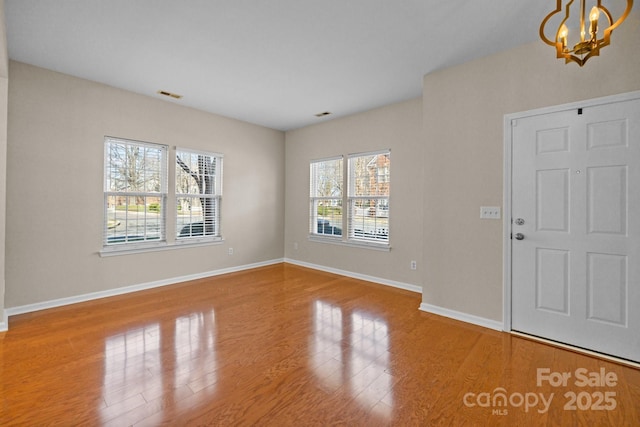 entryway with a chandelier, visible vents, baseboards, and wood finished floors