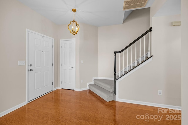foyer entrance with stairs, visible vents, baseboards, and wood finished floors