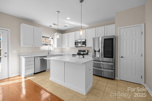 kitchen with white cabinets, light countertops, appliances with stainless steel finishes, a center island, and pendant lighting