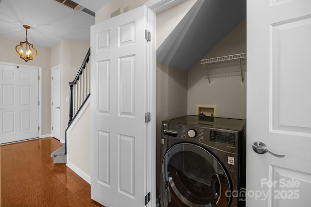 clothes washing area featuring dark wood-style floors, laundry area, washer / clothes dryer, and baseboards