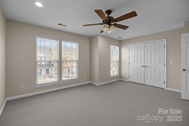 unfurnished bedroom with baseboards, visible vents, a ceiling fan, carpet floors, and a closet
