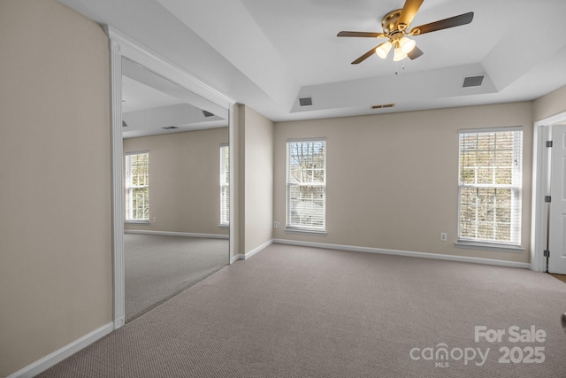spare room featuring carpet flooring, a raised ceiling, and visible vents