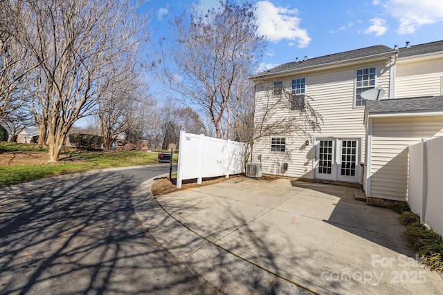 rear view of property featuring a patio area, fence, cooling unit, and french doors
