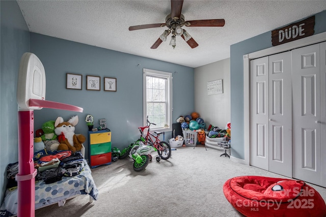 game room with carpet floors, ceiling fan, and a textured ceiling