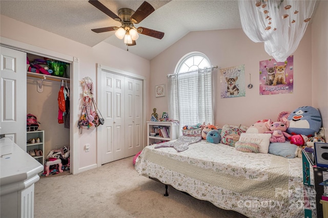 bedroom with multiple closets, vaulted ceiling, carpet floors, and a textured ceiling