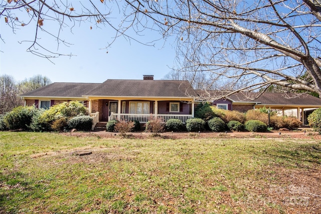 ranch-style house featuring a chimney, brick siding, covered porch, and a front yard