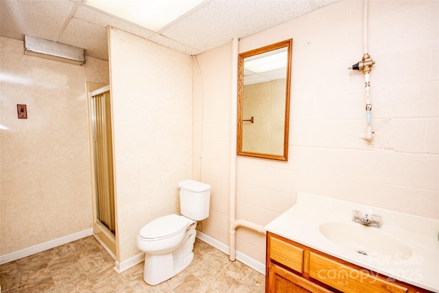 bathroom featuring a drop ceiling, toilet, a stall shower, and vanity