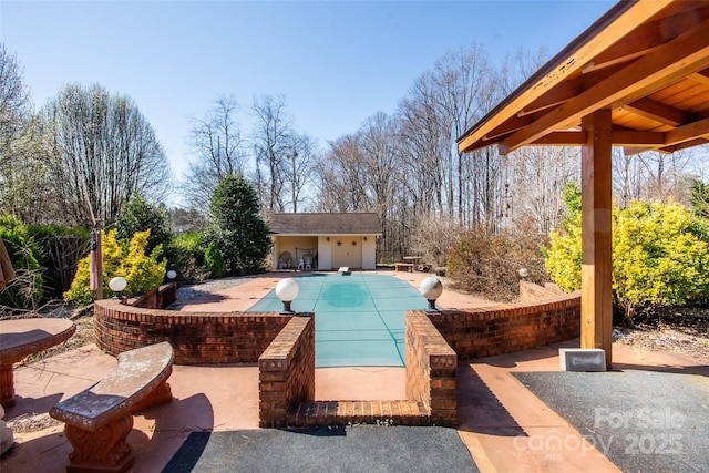 view of swimming pool with a covered pool, an outdoor structure, and a patio