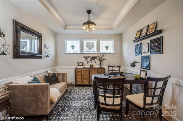 dining area with a wainscoted wall, a tray ceiling, and crown molding