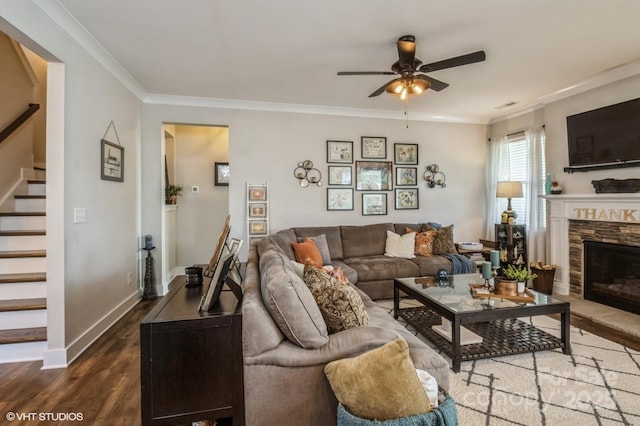 living area with dark wood-style floors, stairway, ornamental molding, a stone fireplace, and baseboards