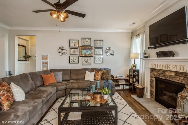 living room featuring light wood finished floors, a fireplace, visible vents, and ornamental molding