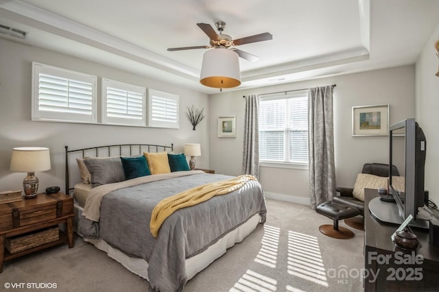 bedroom with baseboards, a raised ceiling, visible vents, and light colored carpet