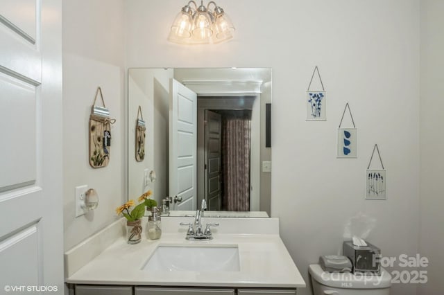 bathroom with a chandelier, vanity, and toilet