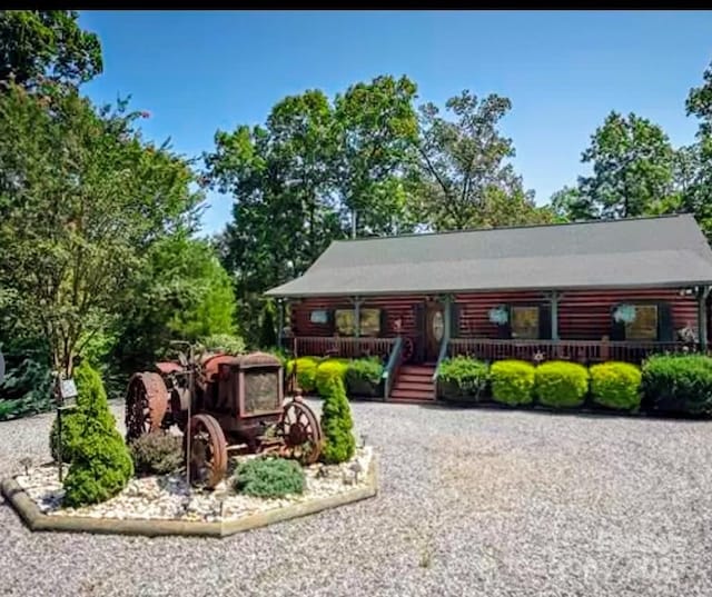 cabin with a porch and gravel driveway