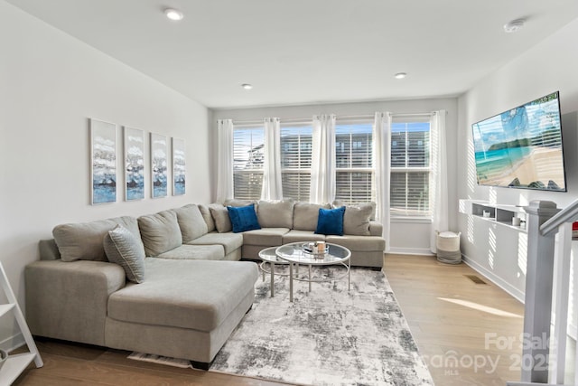 living room featuring recessed lighting, wood finished floors, visible vents, and baseboards