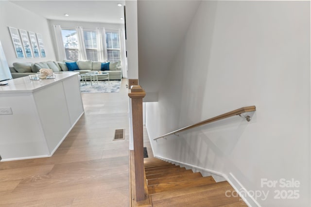 stairs with recessed lighting, visible vents, and wood finished floors