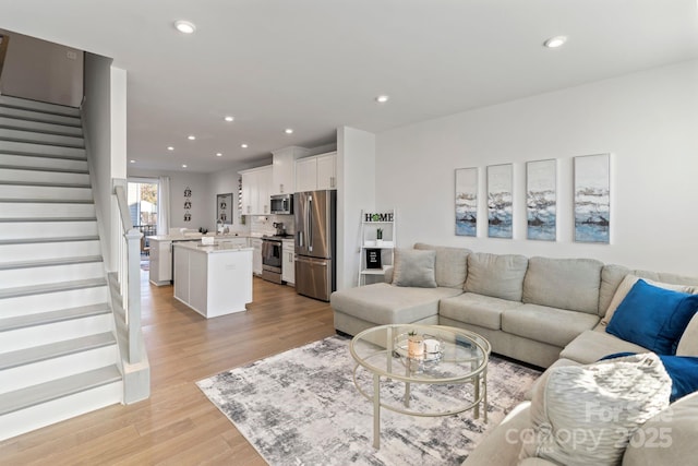 living room with recessed lighting, stairway, and light wood-style flooring