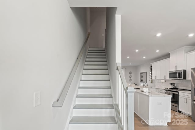 staircase featuring recessed lighting and wood finished floors