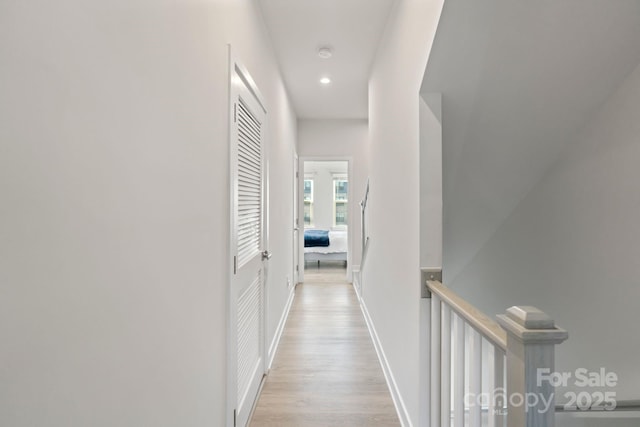 corridor with wood finished floors, recessed lighting, an upstairs landing, and baseboards