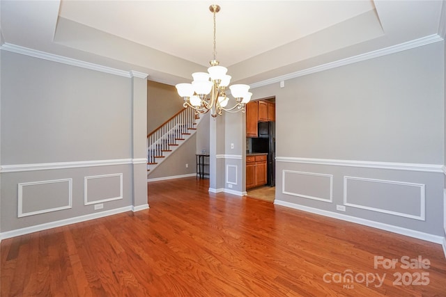 unfurnished dining area featuring light wood-type flooring, a tray ceiling, and stairway