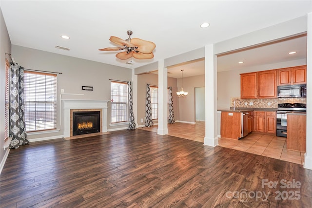 unfurnished living room with light wood-style flooring, recessed lighting, ceiling fan with notable chandelier, and visible vents