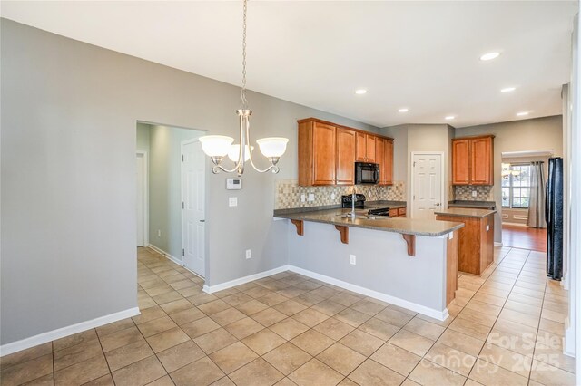 kitchen with tasteful backsplash, a kitchen bar, a peninsula, a notable chandelier, and black appliances