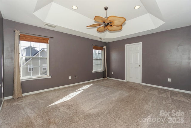 carpeted spare room with visible vents, a ceiling fan, a tray ceiling, recessed lighting, and baseboards