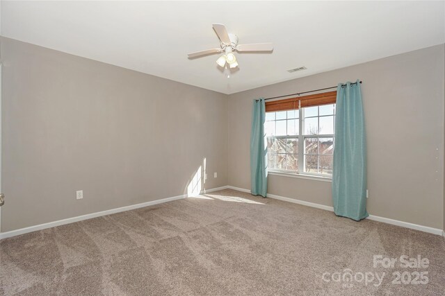 carpeted spare room featuring visible vents, a ceiling fan, and baseboards