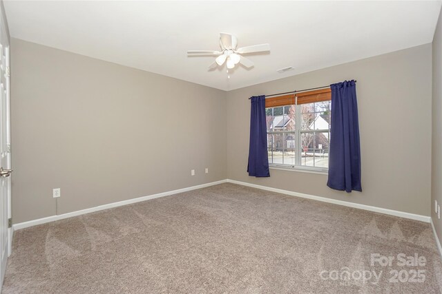 carpeted spare room with visible vents, baseboards, and a ceiling fan