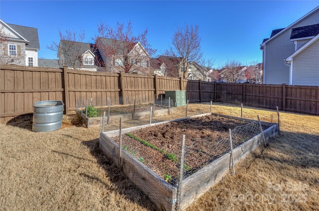 view of yard featuring a fenced backyard, a residential view, and a vegetable garden