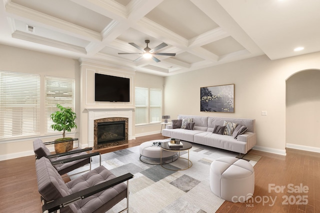 living area with baseboards, arched walkways, wood finished floors, and a high end fireplace