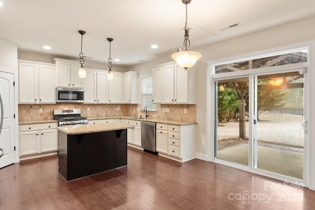 kitchen with a kitchen island, white cabinetry, stainless steel appliances, and decorative light fixtures