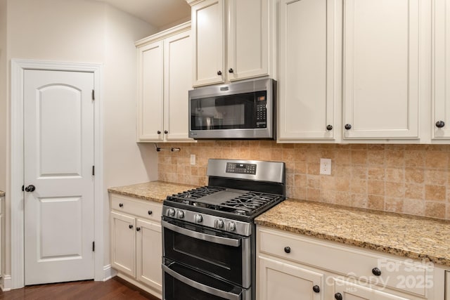 kitchen featuring appliances with stainless steel finishes, backsplash, light stone counters, and dark wood-style floors