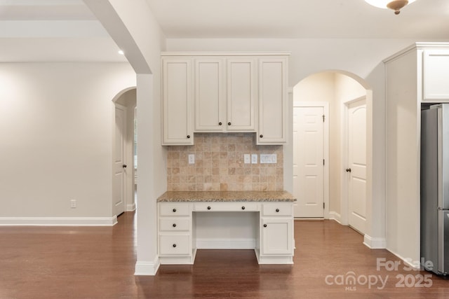 kitchen featuring freestanding refrigerator, white cabinets, dark wood finished floors, and light stone countertops