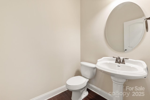 half bathroom with toilet, baseboards, and wood finished floors