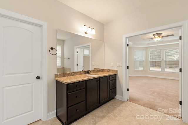 bathroom with a raised ceiling, a ceiling fan, vanity, tile patterned flooring, and baseboards