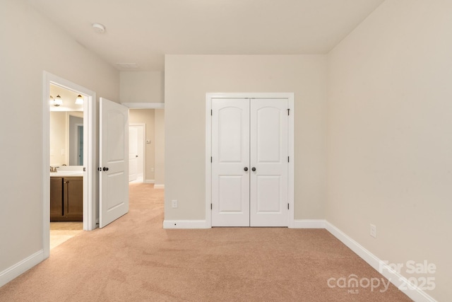 unfurnished bedroom featuring a closet, light carpet, and baseboards