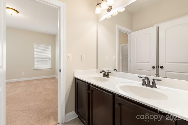 full bathroom featuring double vanity, a sink, and baseboards