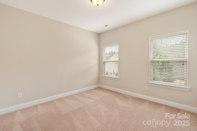 unfurnished room with light carpet, visible vents, and baseboards