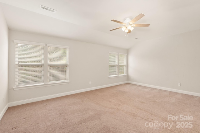 unfurnished room with light carpet, lofted ceiling, visible vents, and baseboards