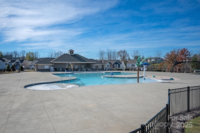 community pool with a residential view, a patio area, and fence