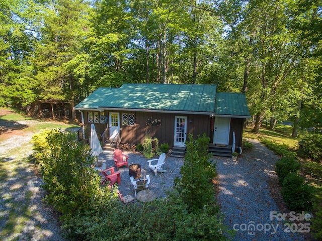 view of front of property featuring entry steps, metal roof, and a fire pit