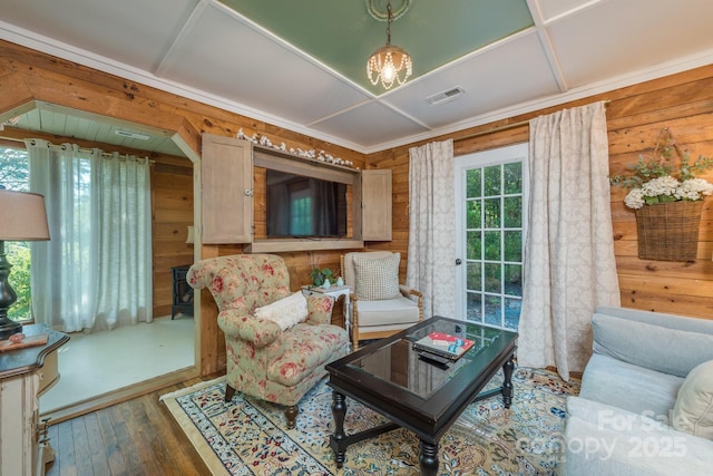 living area with a chandelier, wood walls, wood finished floors, and visible vents