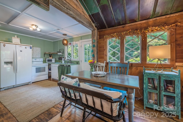 dining room with wood finished floors, visible vents, and wooden walls