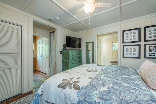 bedroom with ceiling fan, visible vents, and wood finished floors