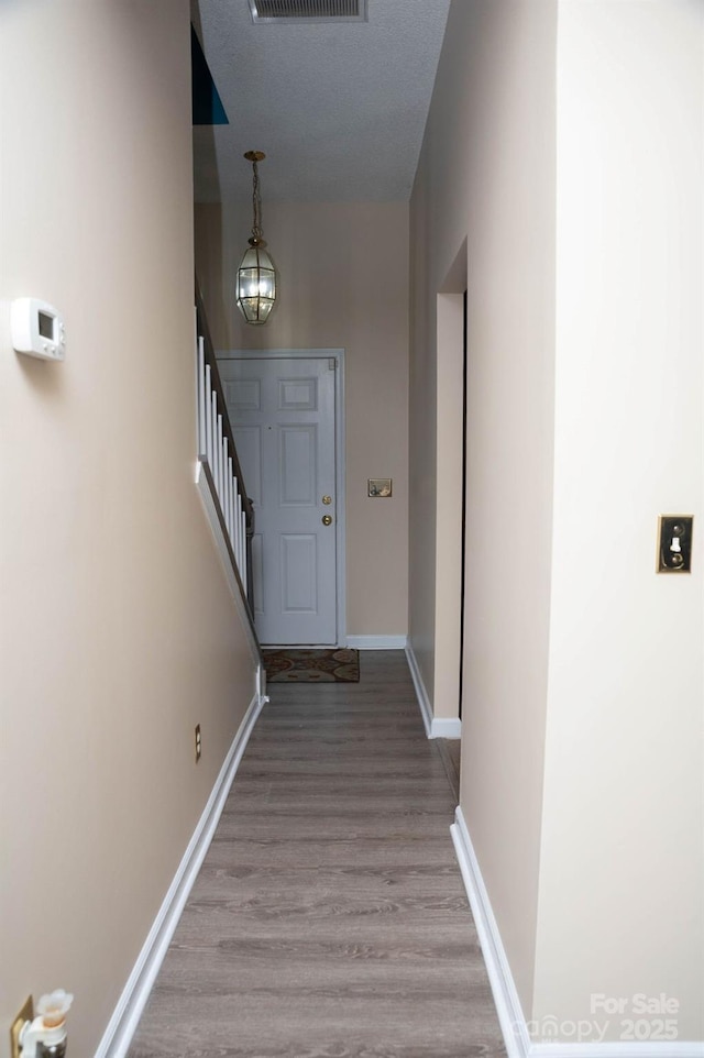 doorway to outside featuring visible vents, stairway, wood finished floors, a chandelier, and baseboards