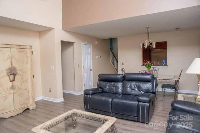 living room with a chandelier, stairway, wood finished floors, and baseboards