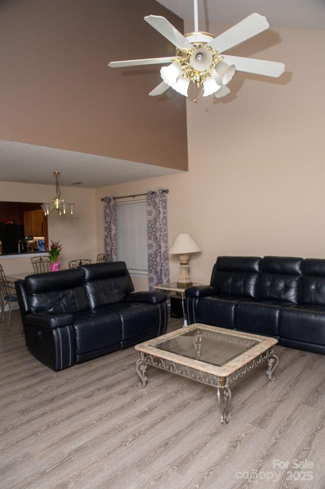 living room with a high ceiling, light wood-style flooring, and a ceiling fan