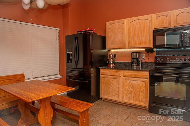 kitchen with black appliances, light tile patterned floors, light brown cabinets, and dark stone counters