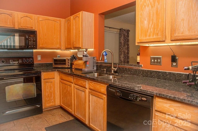 kitchen featuring light tile patterned floors, black appliances, dark stone countertops, and a sink